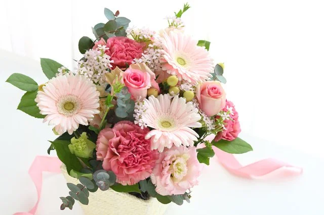 白い器に重ねた淡い色の花々と枝を使ったテーブル装花