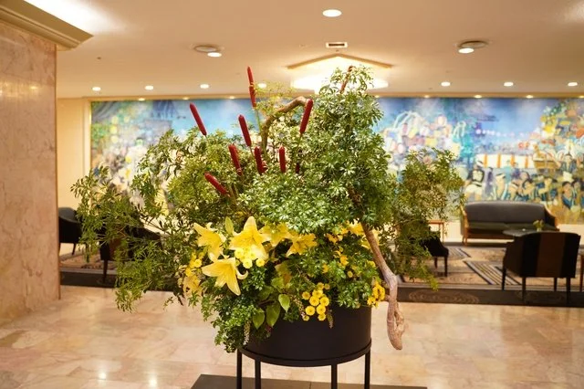 大きな窓のある会場に設置された枝ものと季節の花による空間装花