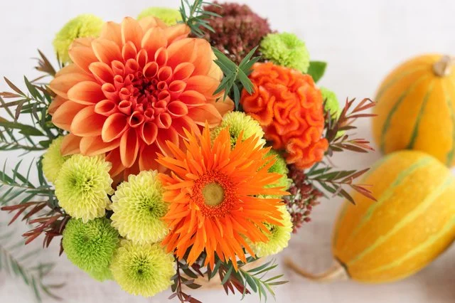 淡い色合いの花を包んだ手渡し用のフラワーギフト
